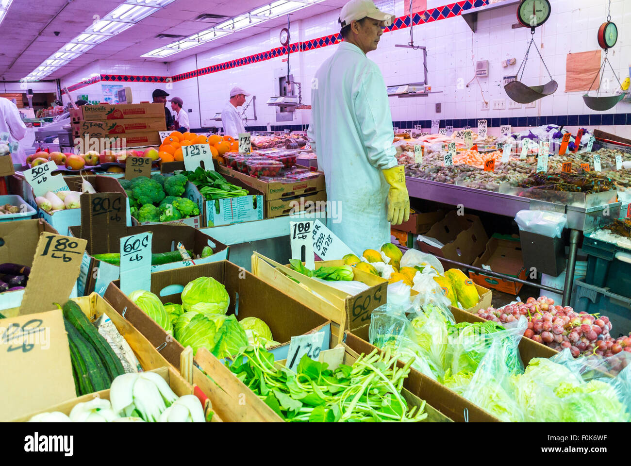 New York City, USA,  Clerk inside Chinese neighborhood grocery store vegetables in Chinatown District,  on Display, immigrant labor, man standing from behind, migrants inside nyc Stock Photo