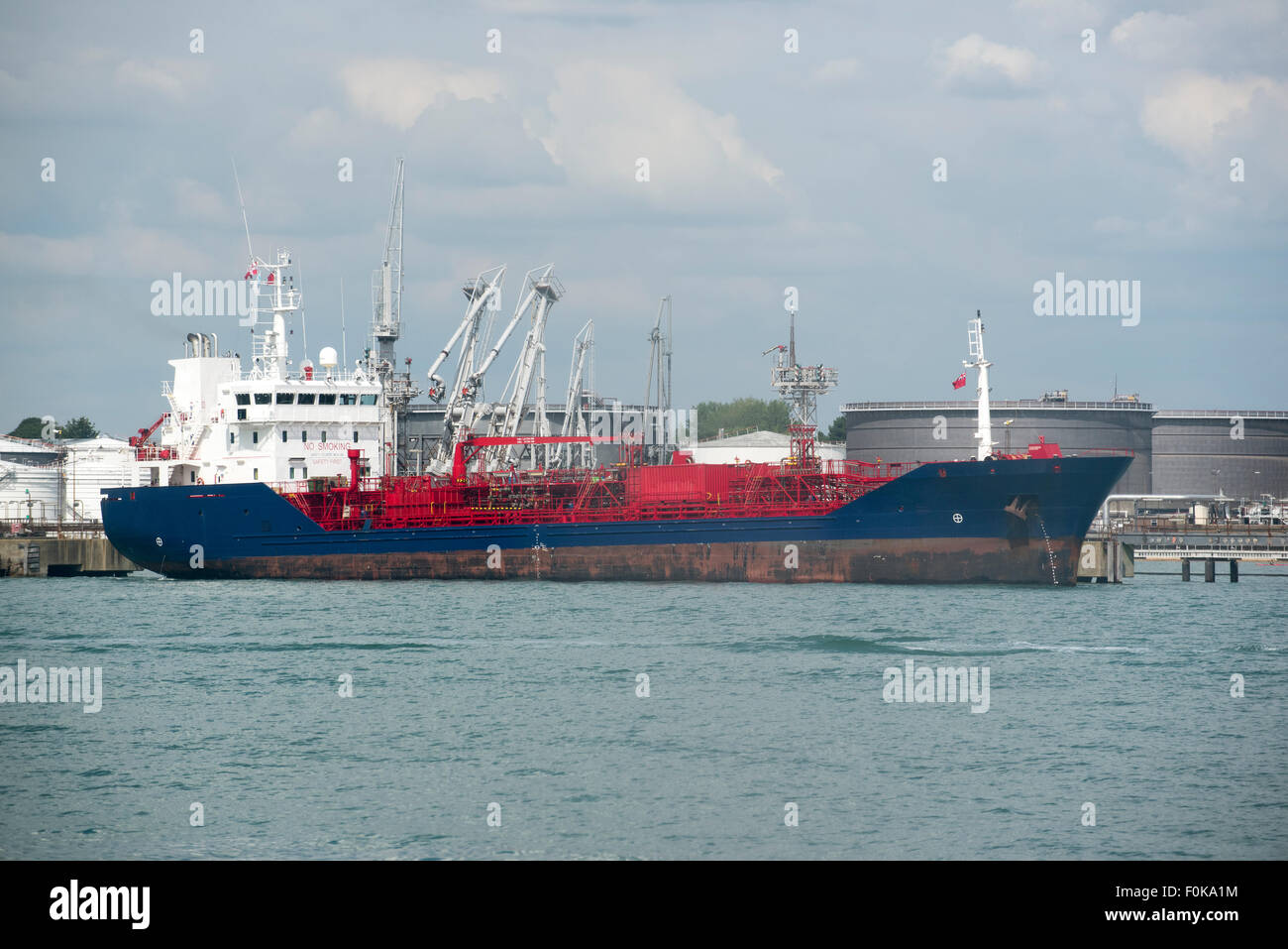Oil tanker ship unloading its cargo of fuel to storage tanks Stock