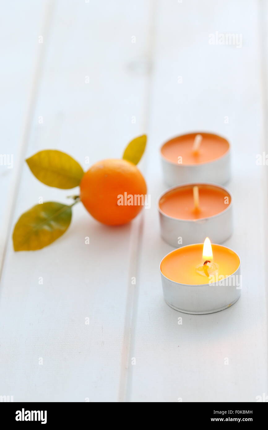 Citrus scented candles with citrus fruit on wooden board Stock Photo