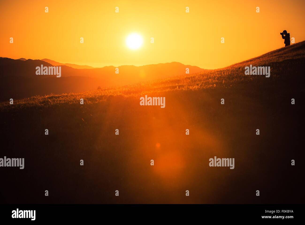 Nature and Travel Photographer on the Hill During Scenic Sunset. Northern California Landscape. Stock Photo