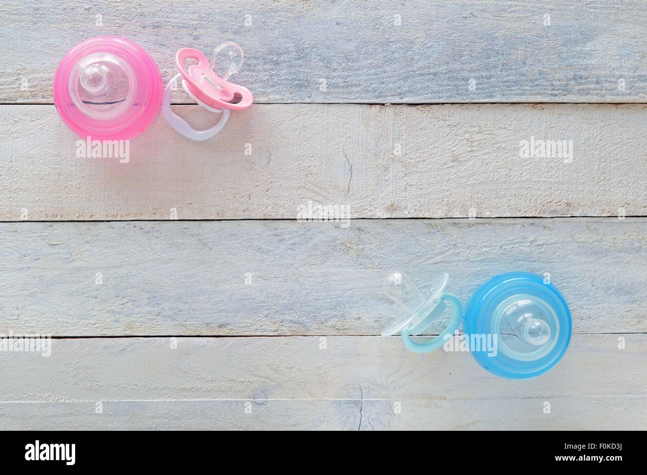 Pink and Blue pacifiers and baby bottles representing both girl and boy. Empty space for editor's text. Copy space Stock Photo