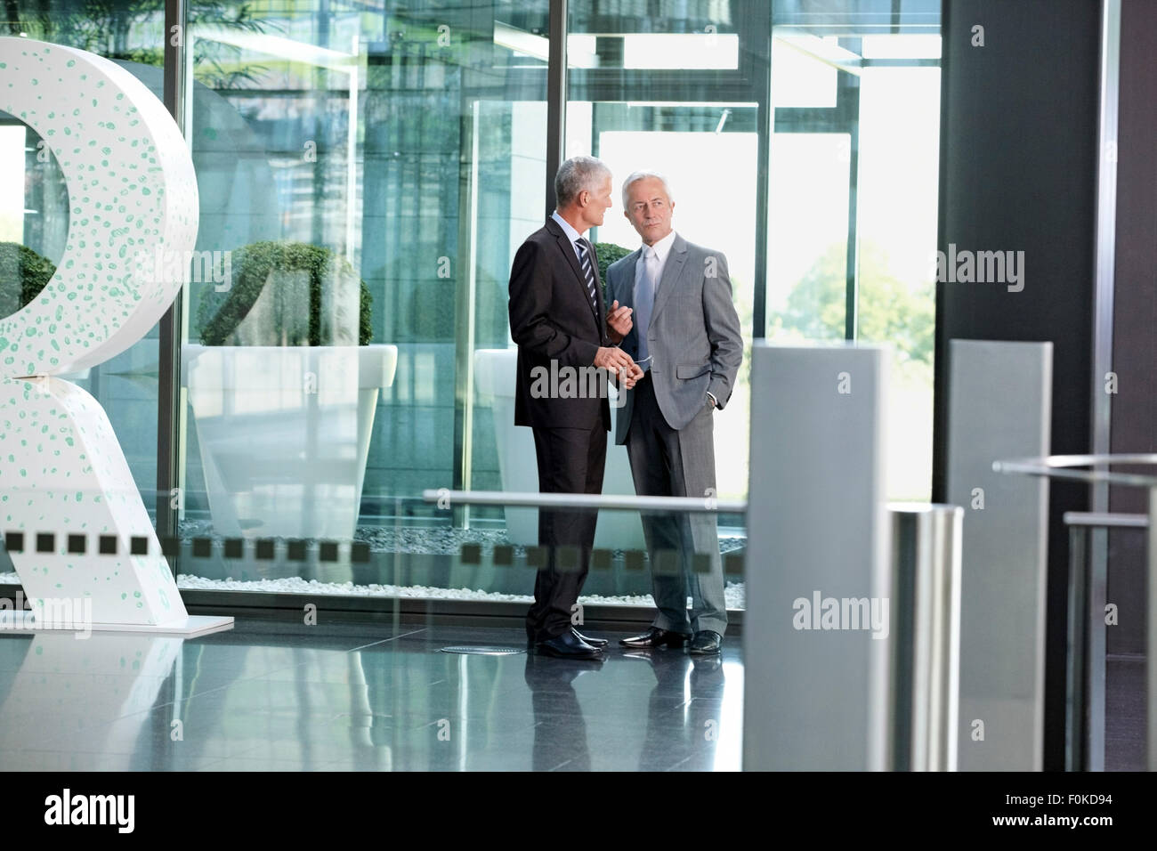 Two businessmen talking in office lobby Stock Photo - Alamy