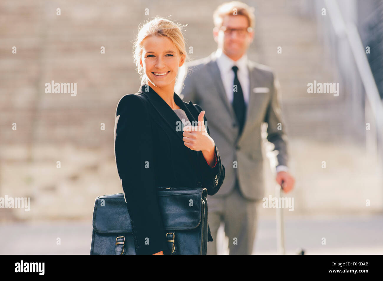 Optimistic businesswoman with businessman in background Stock Photo