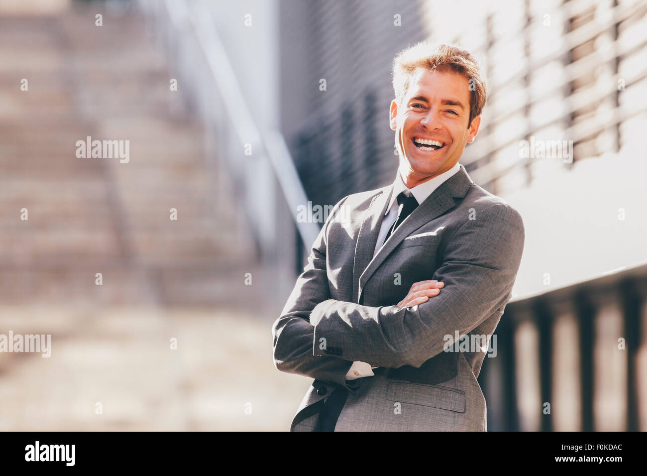 Happy businessman with crossed arm outdoors Stock Photo - Alamy