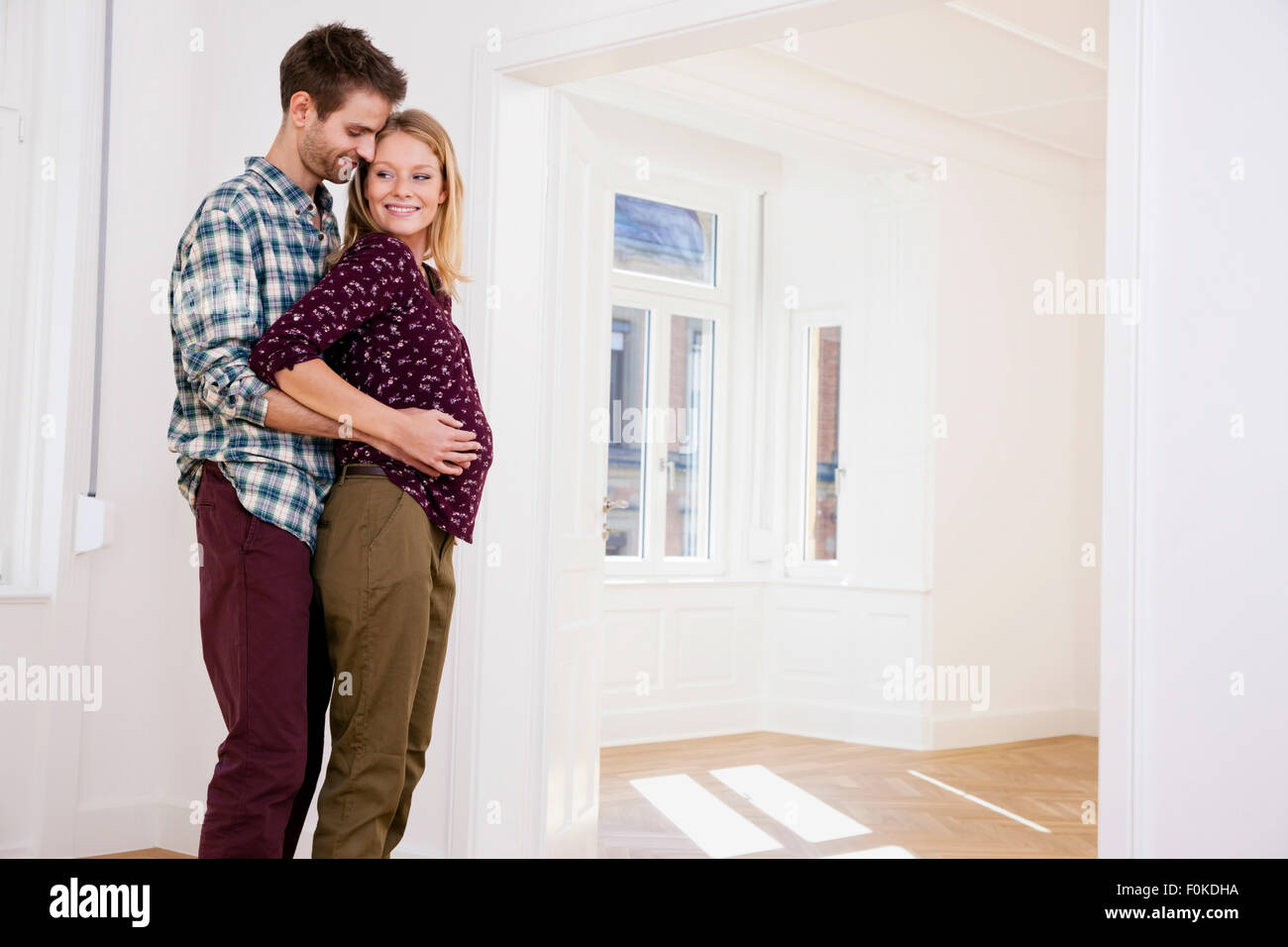 Young man embracing pregnant woman in new home Stock Photo - Alamy