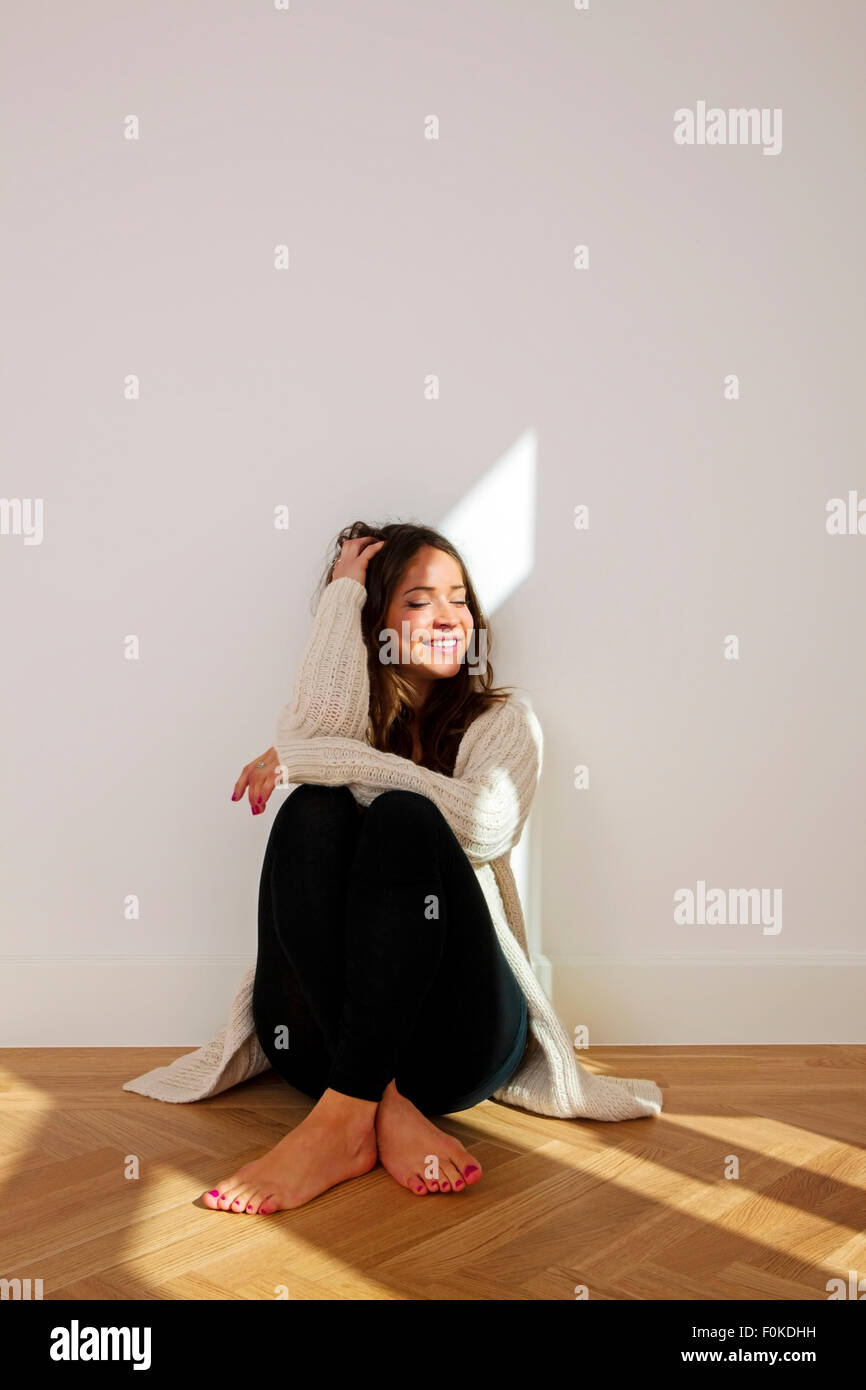 Smiling young woman sitting on floor Stock Photo - Alamy