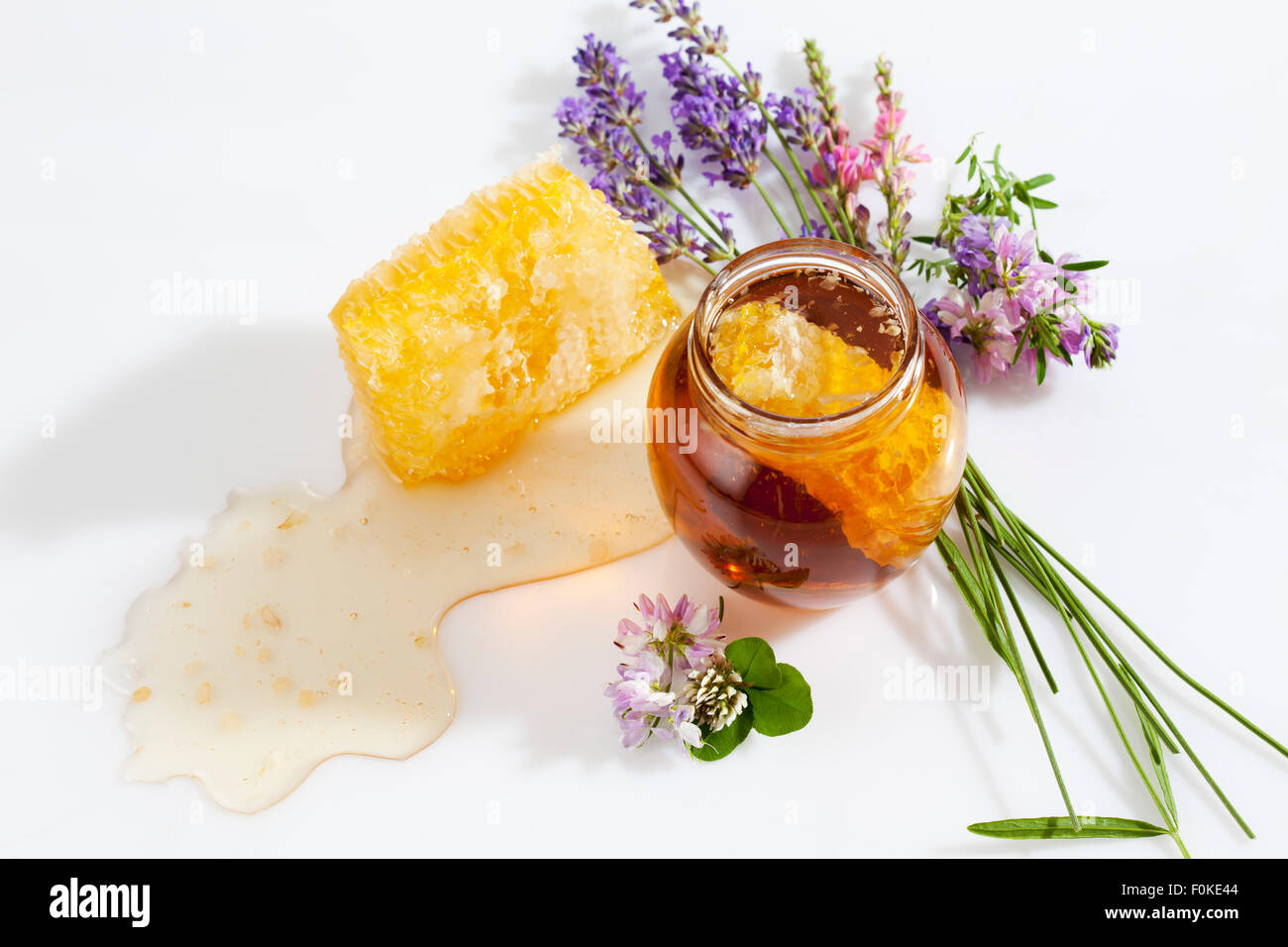 Glass of honey, honeycomb and wild flowers Stock Photo