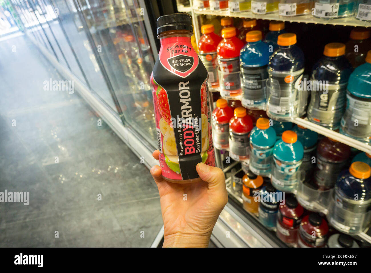 A shopper chooses a bottle of BodyArmor sports drink in a convenience store in New York on Thursday, August 13, 2015. Dr Pepper Snapple Group has bought an 11.7% interest  for $20 million in BodyArmor, a competitor to Gatorade. NBA player Kobe Bryant is also an investor. The drink is considered healthier than its rivals Gatorade and Powerade as it uses cane sugar, not high-fructose corn syrup as a sweetener.  (© Richard B. Levine) Stock Photo