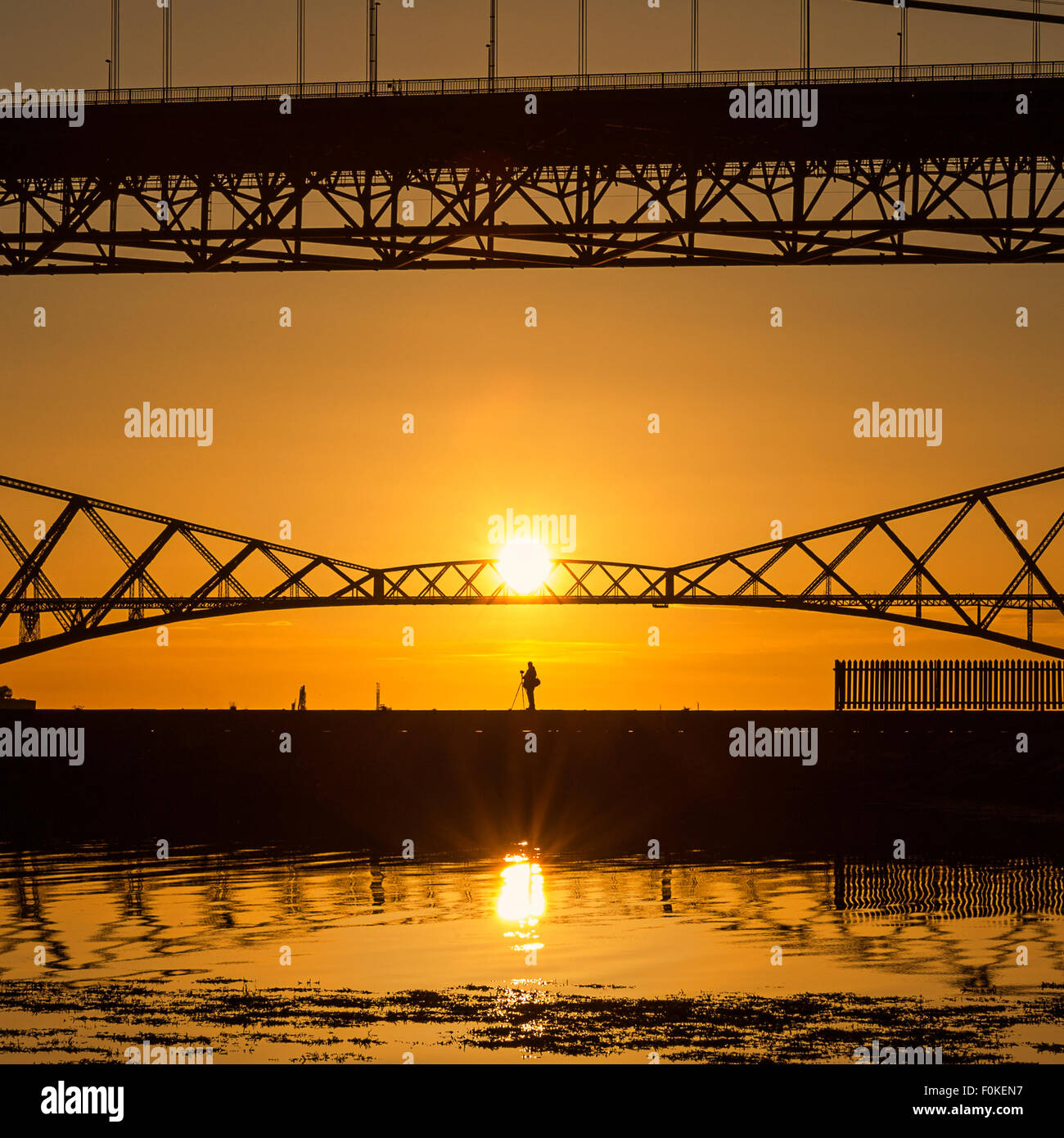 A photographer captures the sunrise over the Forth Bridges from Port Edgar Marina, South Queensferry, Scotland UK Stock Photo