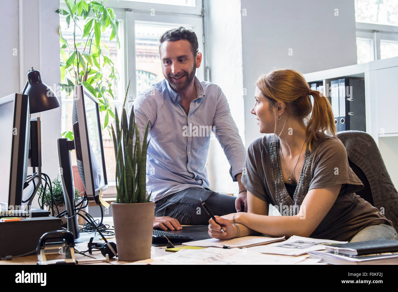 Man and woman in office talking at desk Stock Photo - Alamy
