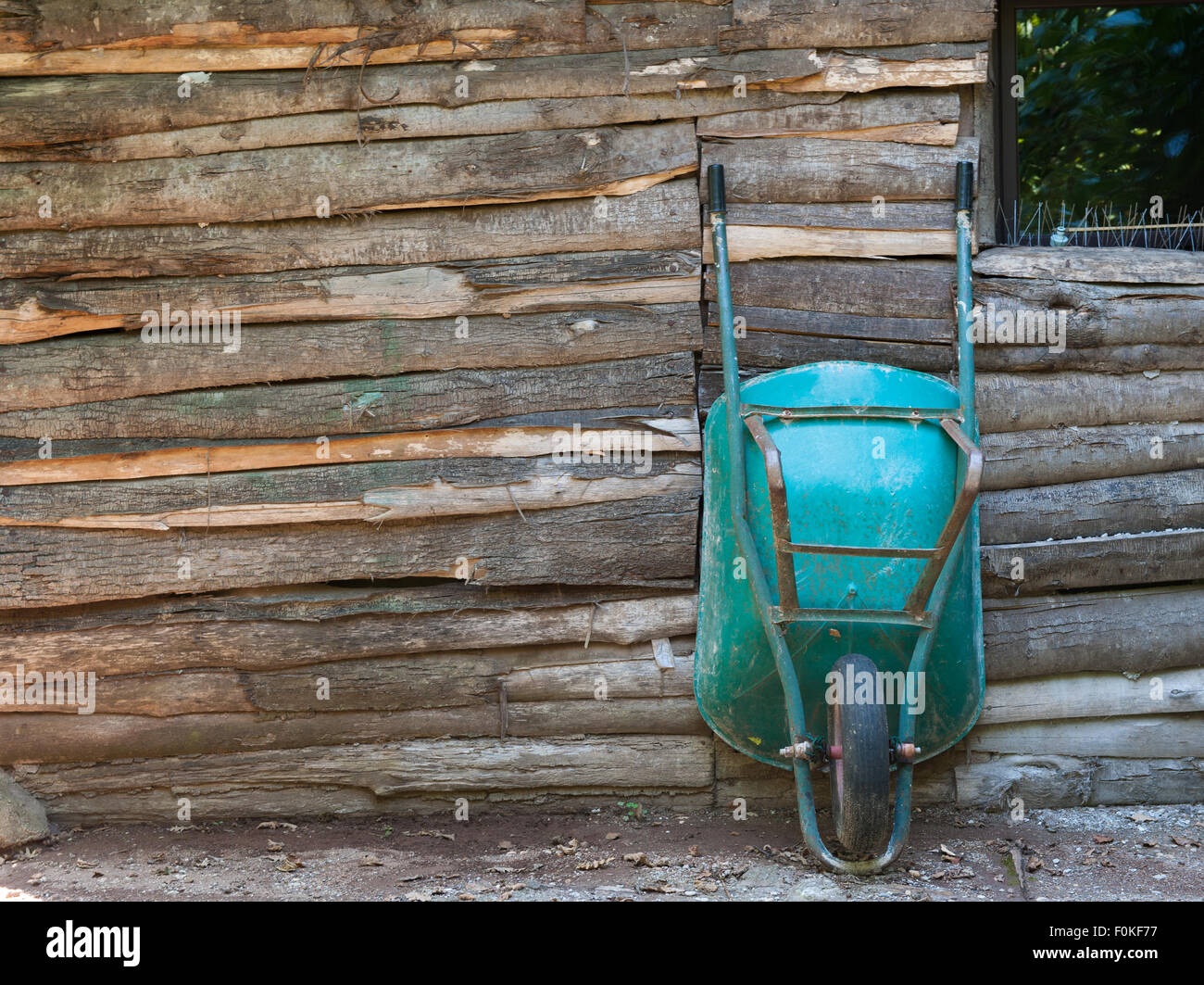 Old aged wheelbarrow on wooden wall in rural farm Stock Photo