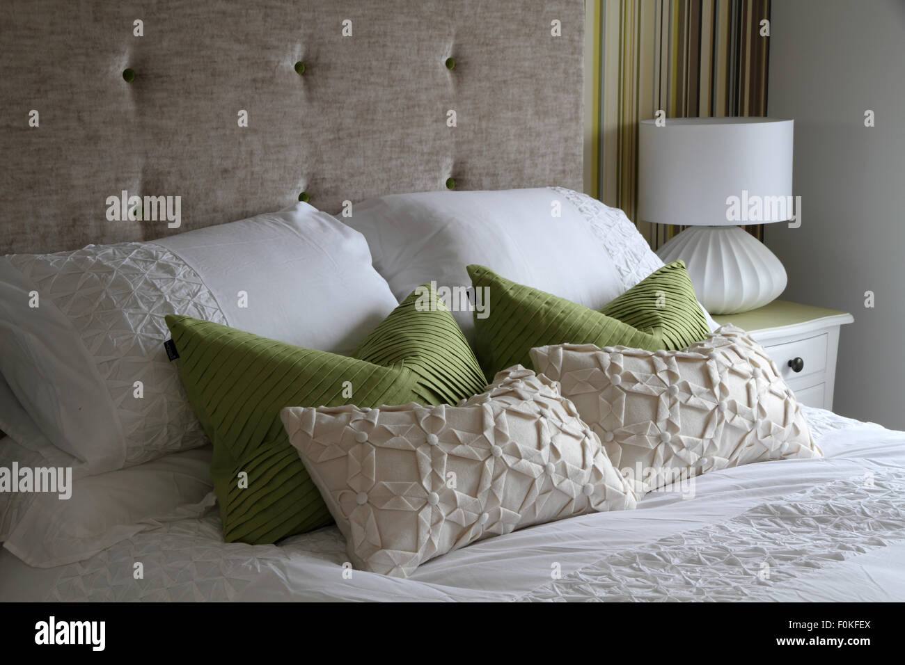 Bed with pillows, cushions and bedside lamp Stock Photo