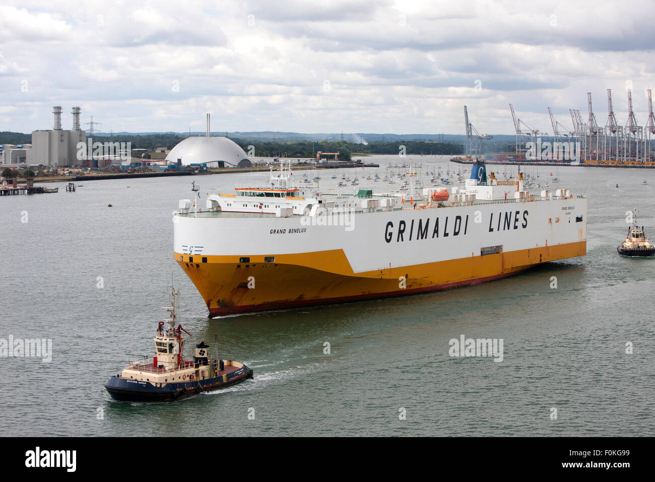 Grimaldi Lines Grand Benelux vehicles carrier ship escorted by 2 tugs at Southampton Port, England Stock Photo