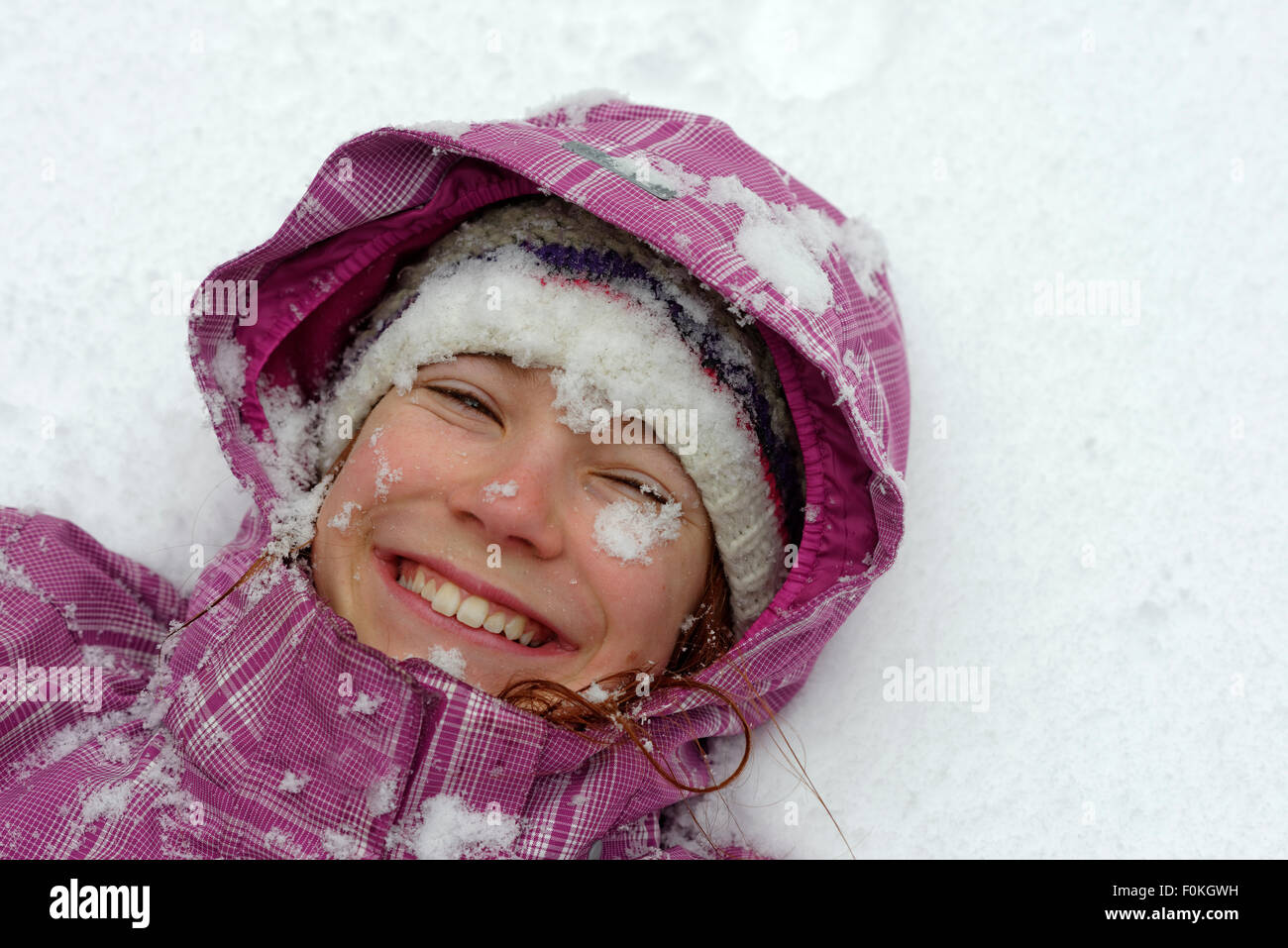 Portrait of smiling girl lying on snow Stock Photo - Alamy