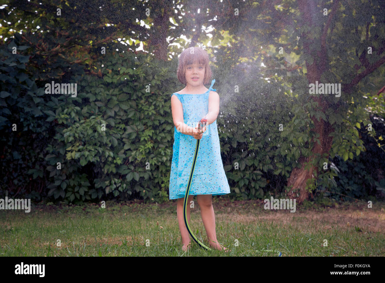 Little girl with garden hose Stock Photo