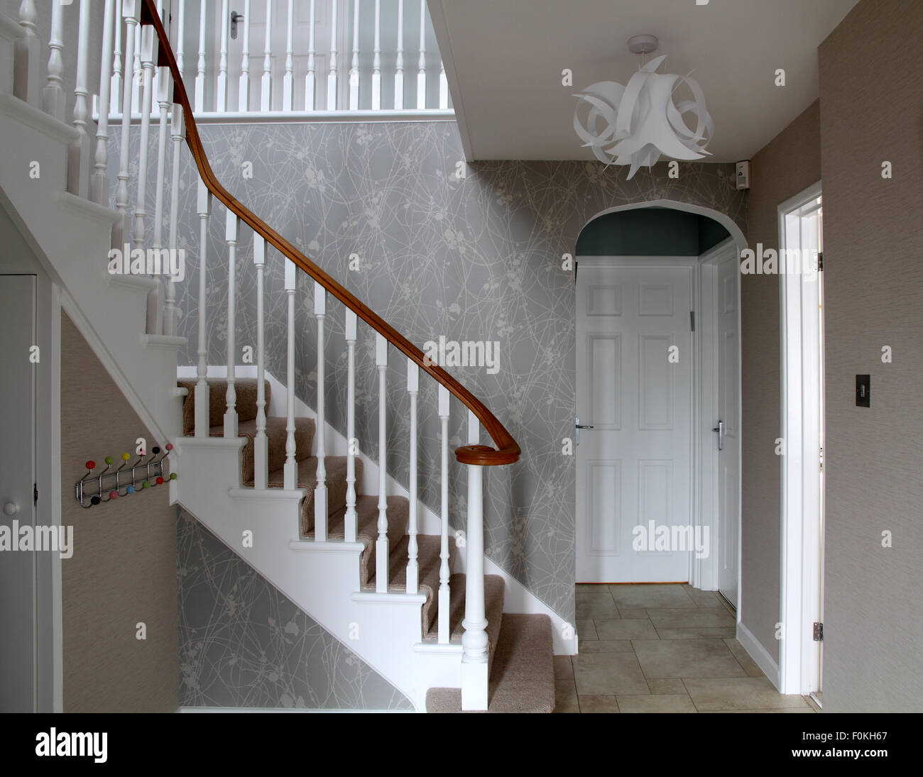 Hall with stairs, white doors, coat hangers and origami style ceiling lamp  shade Stock Photo - Alamy