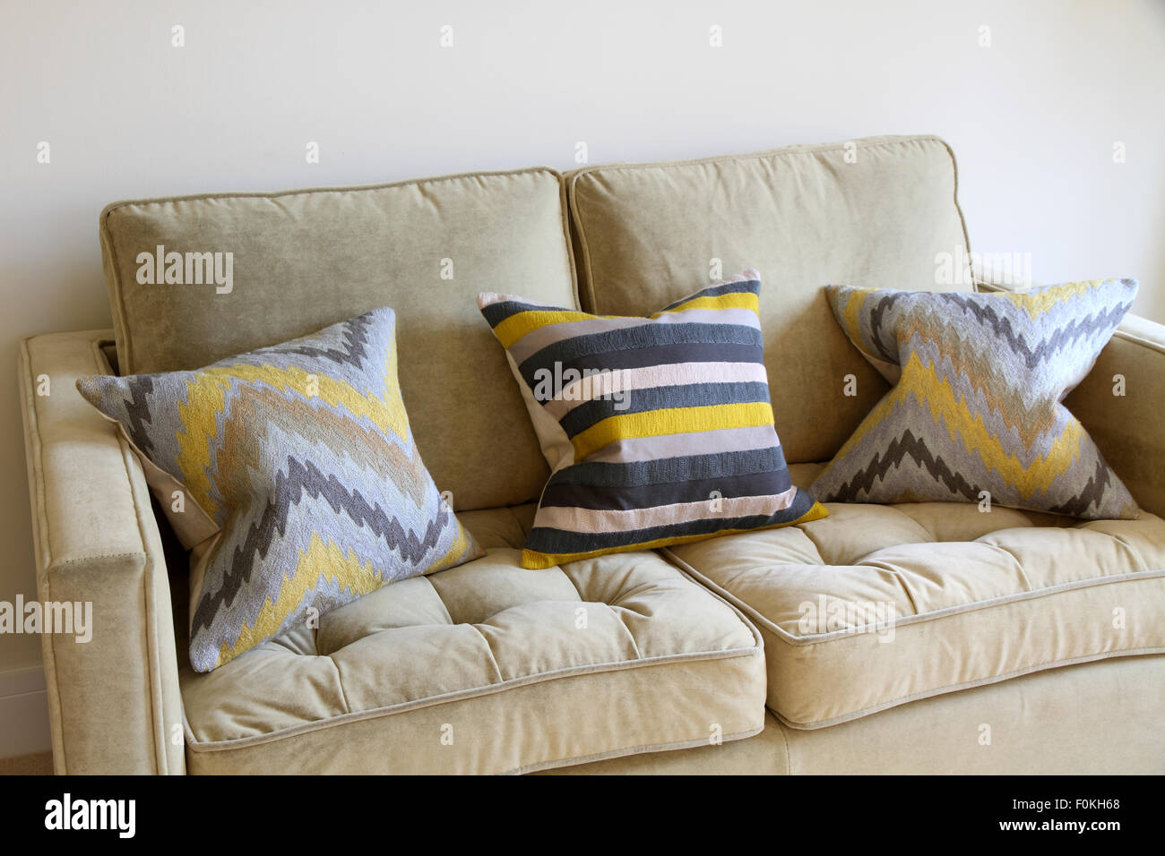 Neutral sofa with yellow,grey and white patterned cushions Stock Photo