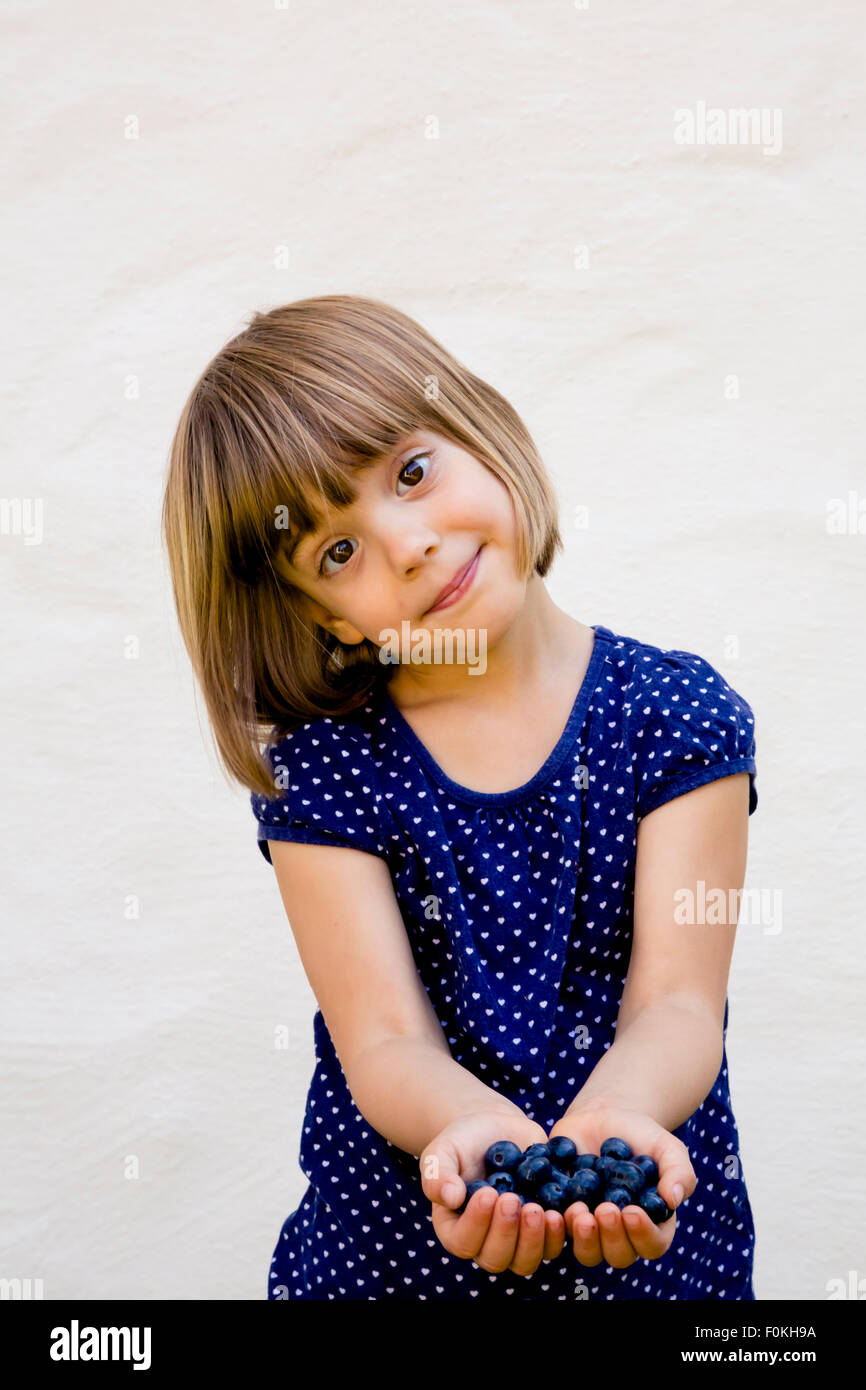 Portrait of little girl with two handfuls of blueberries Stock Photo