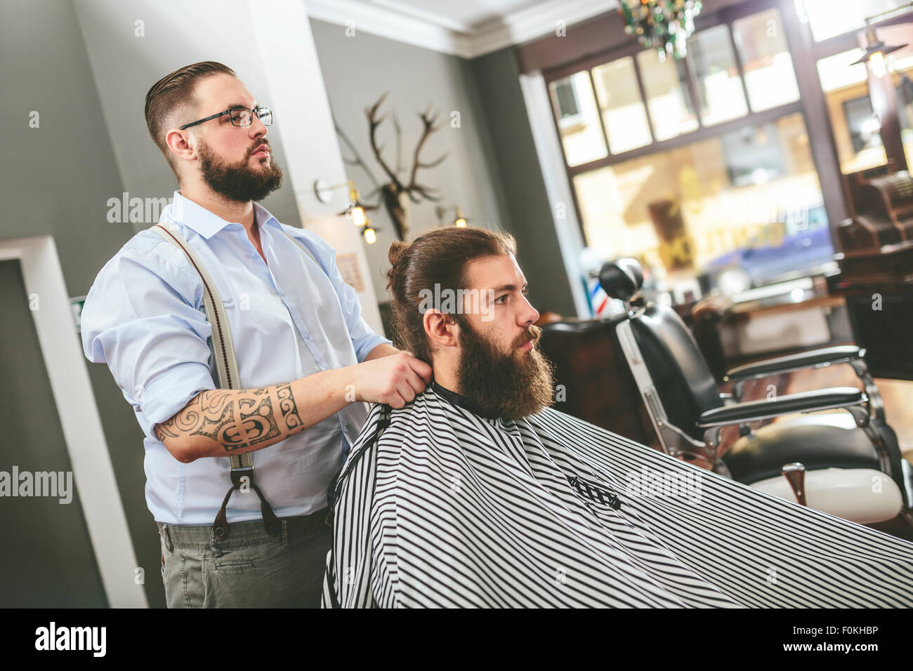 Barber tying cape around customer Stock Photo - Alamy