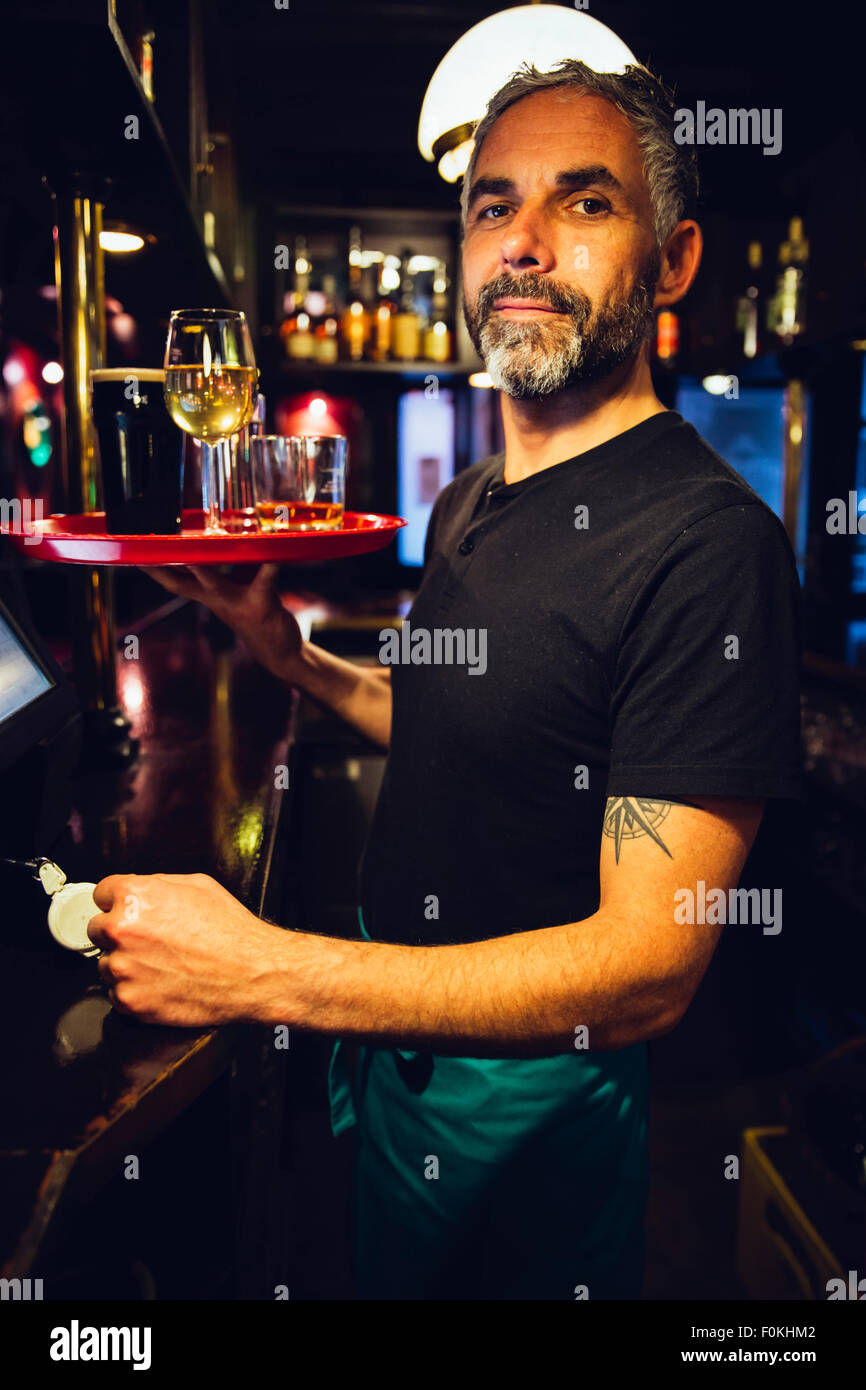 Portrait of a waiter holding tray in an Irish pub Stock Photo