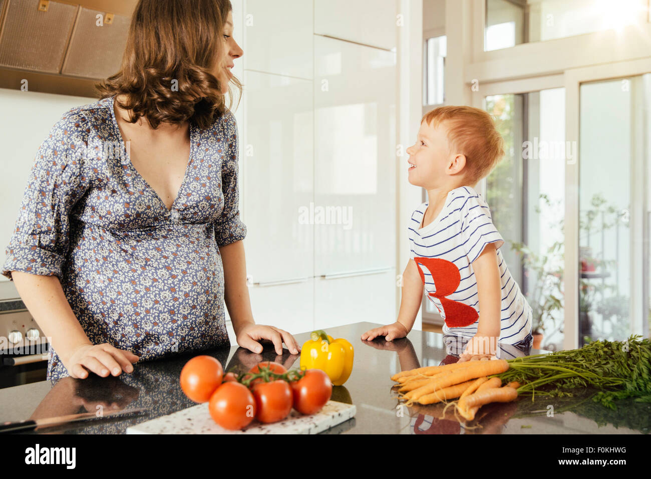 Pregnant woman with her little son in the kitchen Stock Photo