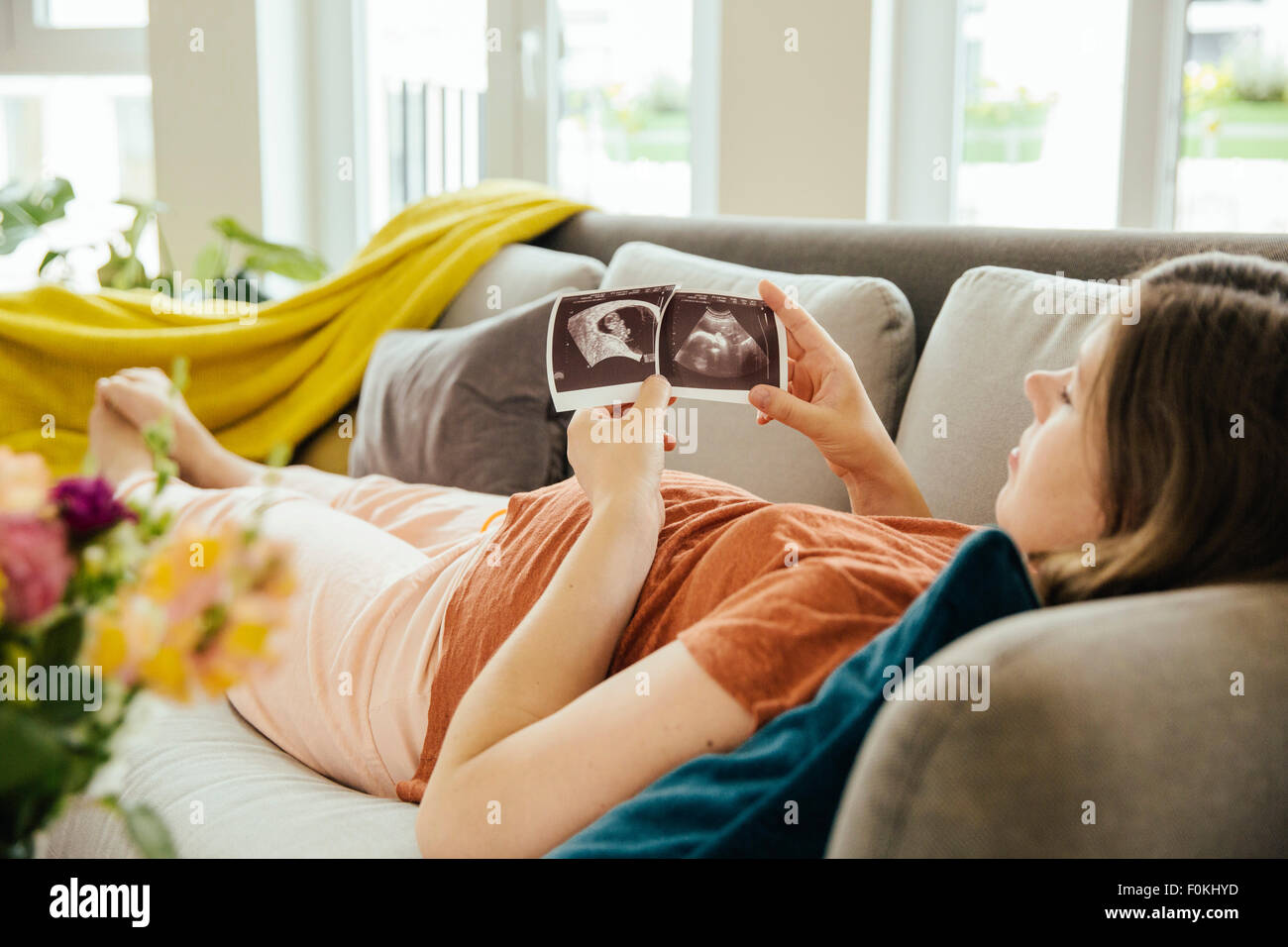 two pregnant women looking ultrasound photo album in living room Stock  Photo