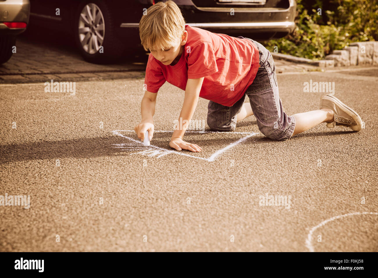 Boy using sidewalk chalk in his neighborhood Stock Photo - Alamy