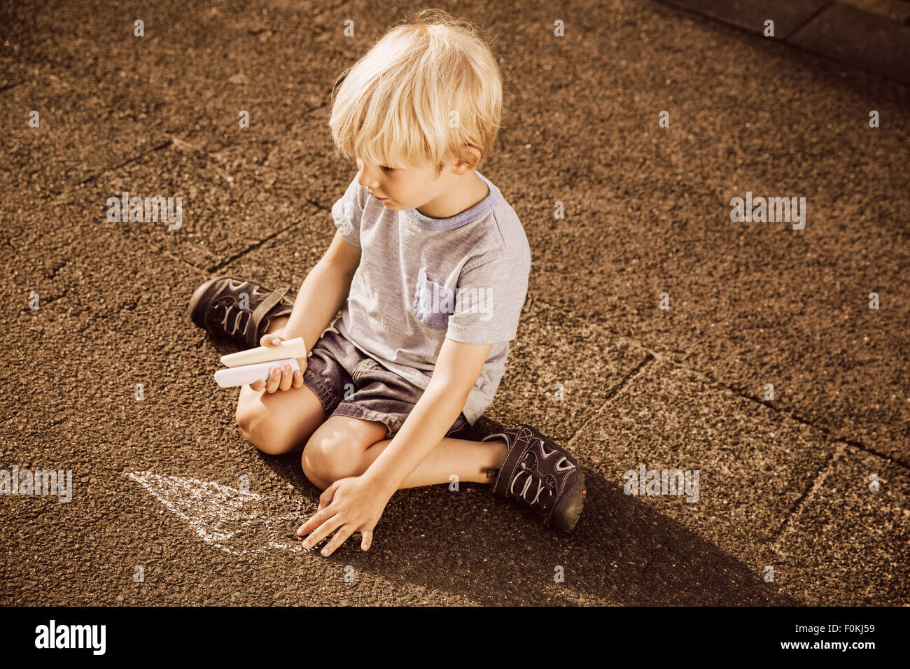Boy using sidewalk chalk on tarmac Stock Photo - Alamy