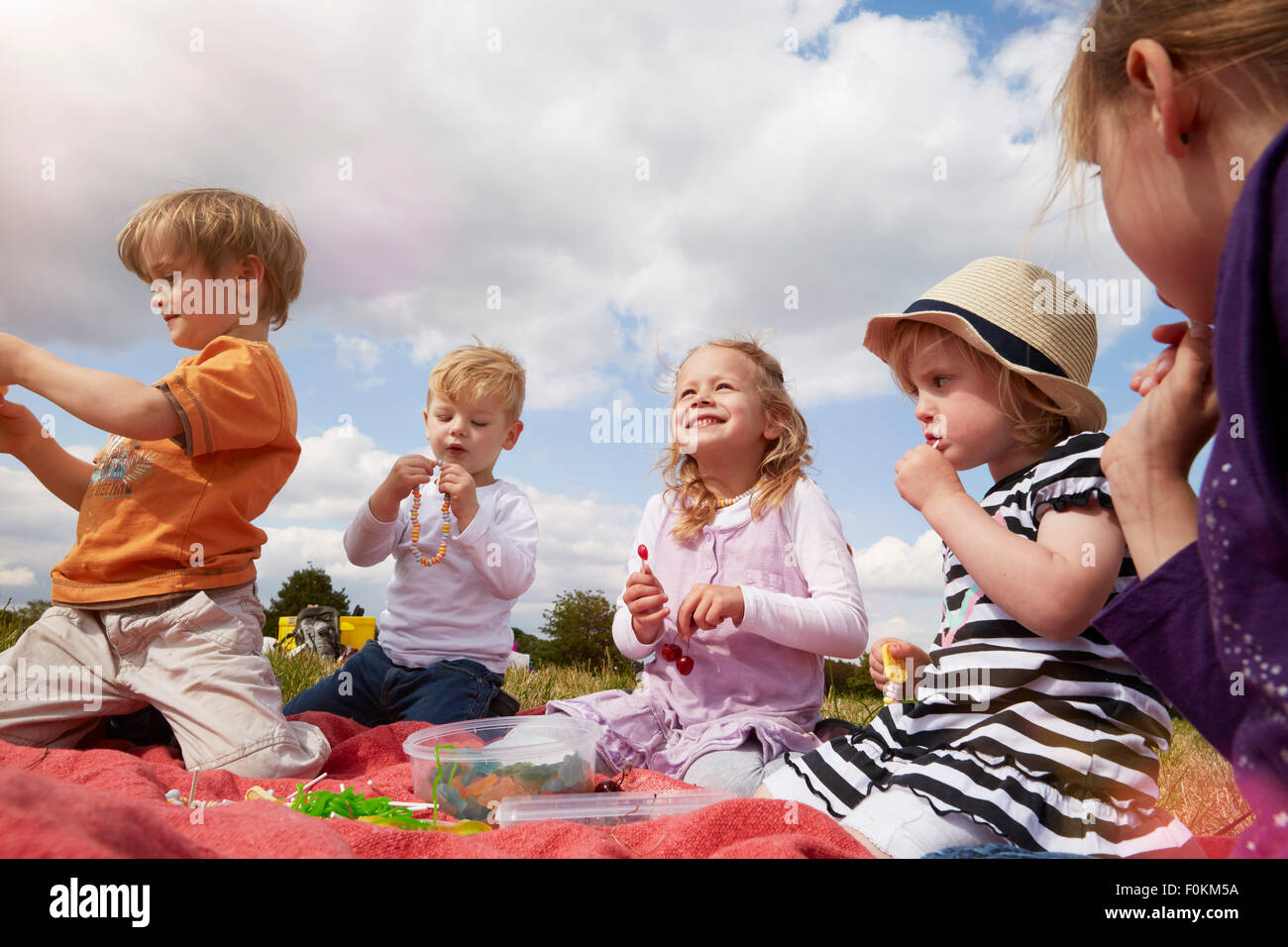 Children sitting on a blanket eating sweets Stock Photo Alamy