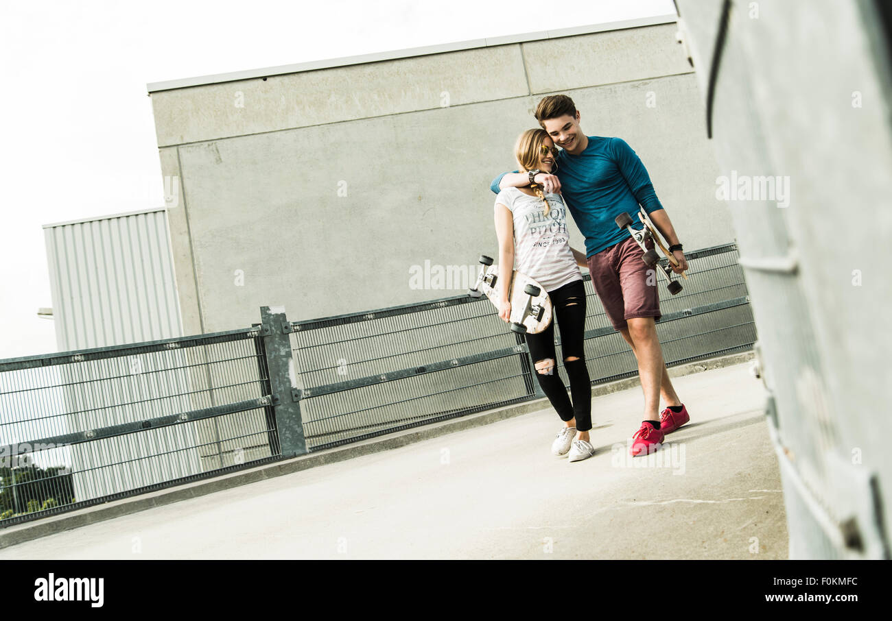 Happy young couple walking with skateboards Stock Photo
