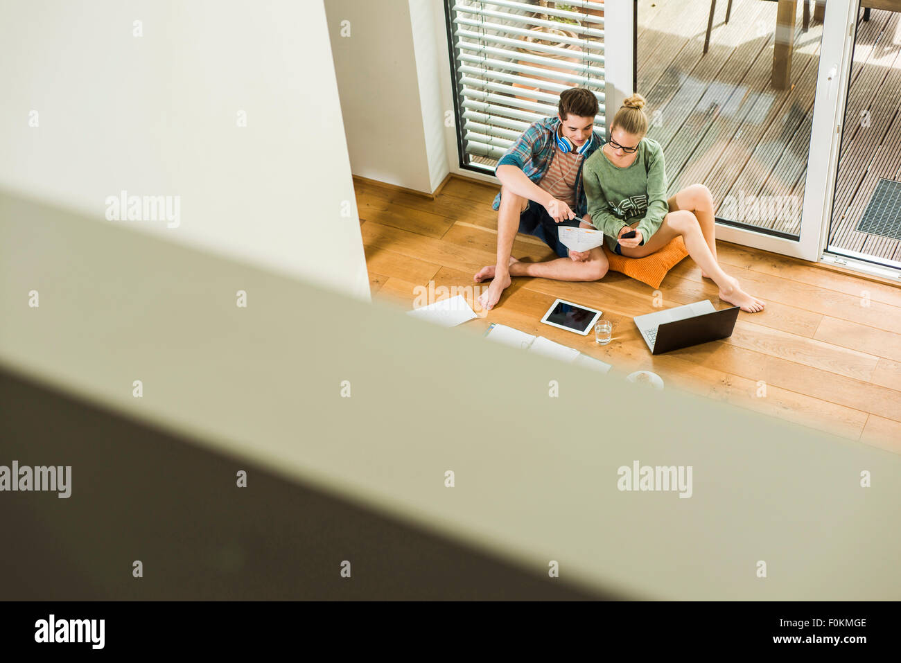 Two students sitting on wooden floor learning Stock Photo