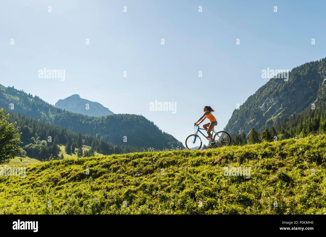Austria, Tyrol, Tannheim Valley, young woman on mountain bike in alpine landscape Stock Photo