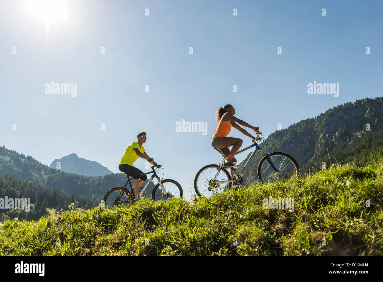 Austria, Tyrol, Tannheim Valley, young couple on mountain bikes in alpine landscape Stock Photo