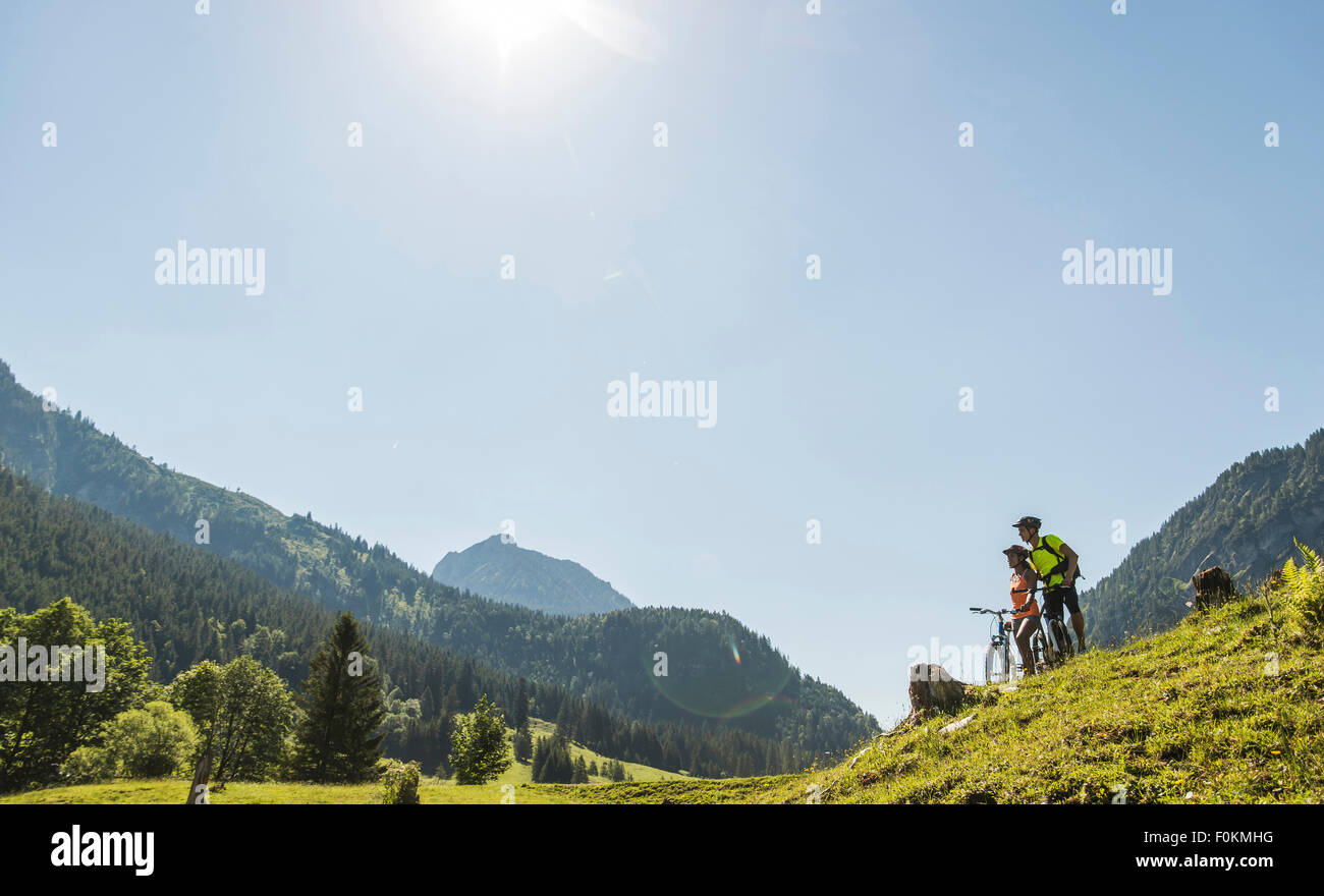 Austria, Tyrol, Tannheim Valley, young couple on mountain bikes in alpine landscape Stock Photo