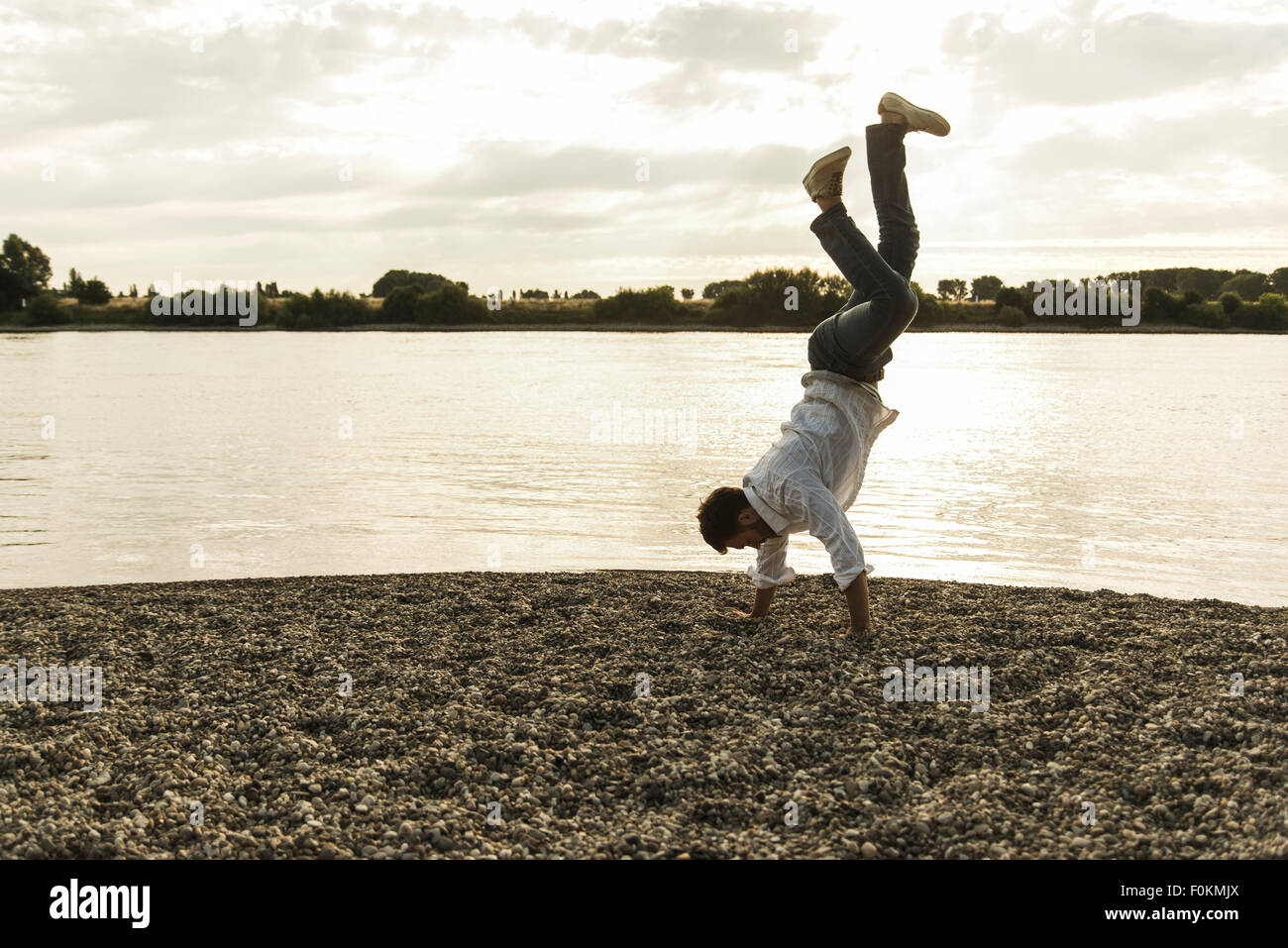 Young man doing a handstand by the riverside Stock Photo