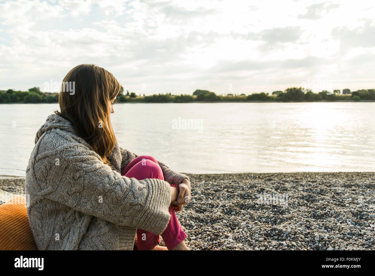Young woman sitting by the riverside Stock Photo