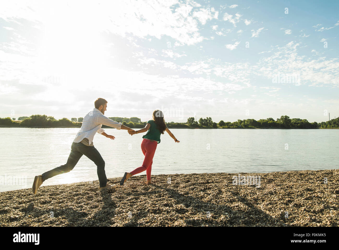 Young couple running hand in hand by the riverside Stock Photo