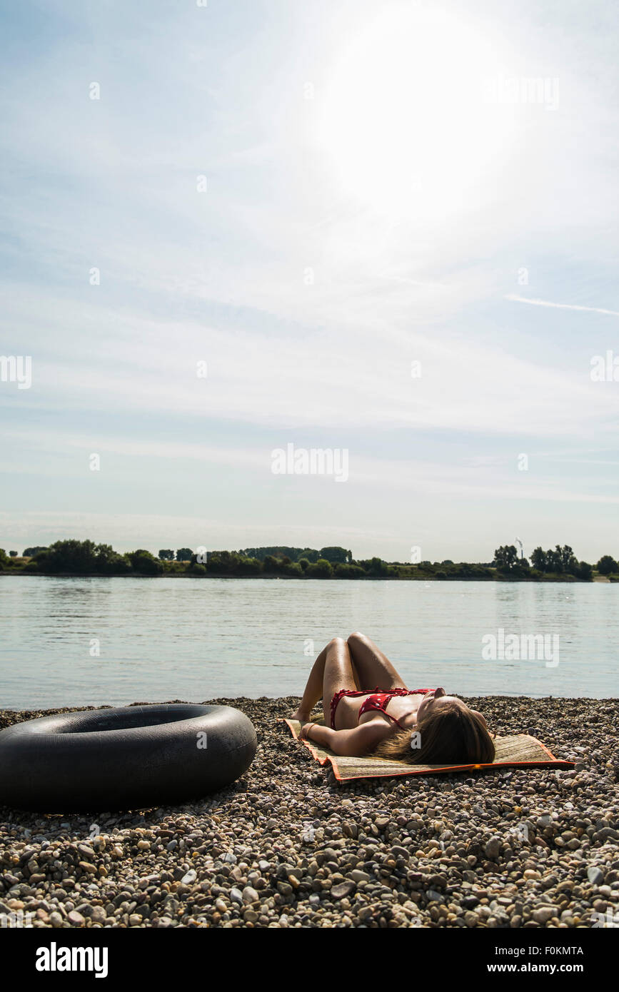 Young woman in bikini sunbathing by the riverside Stock Photo - Alamy