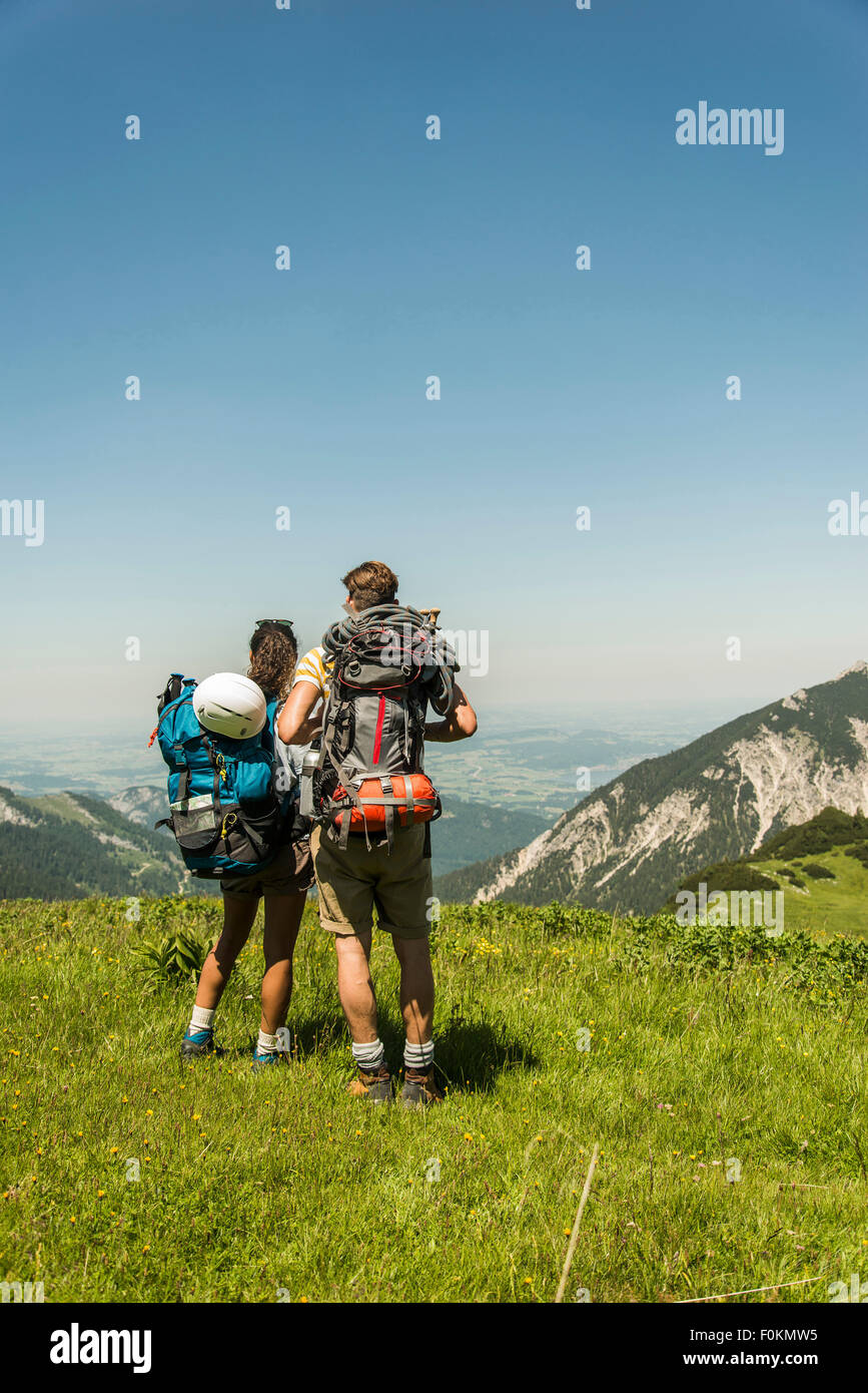 Austria, Tyrol, Tannheimer Tal, young couple standing on alpine meadow looking at view Stock Photo