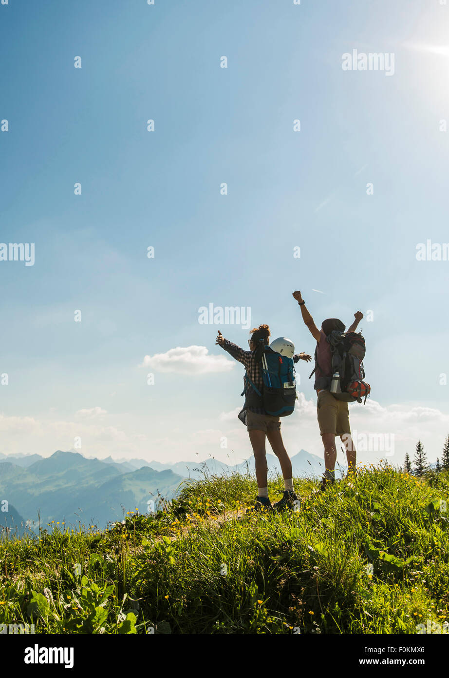 Austria, Tyrol, Tannheimer Tal, cheering young couple standing on mountain trail looking at view Stock Photo