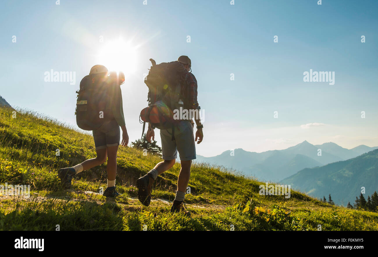 Austria, Tyrol, Tannheimer Tal, young couple hiking on alpine meadow in backlight Stock Photo