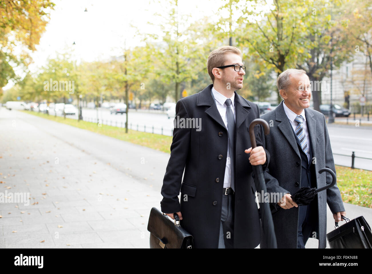 Two businessmen walking and talking on pavement Stock Photo - Alamy