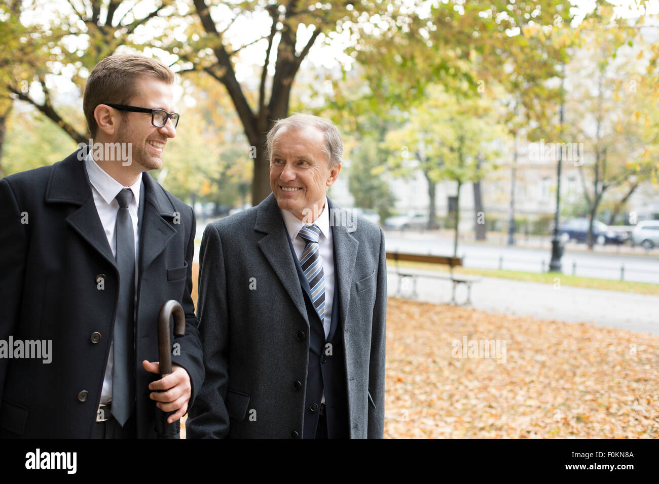 Two businessmen walking and talking in park Stock Photo - Alamy