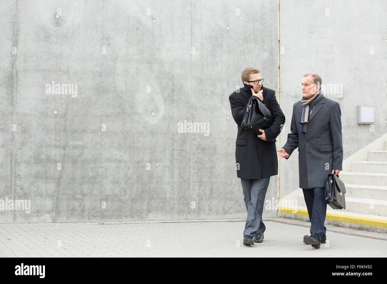 Two businessmen walking and talking outdoors Stock Photo - Alamy