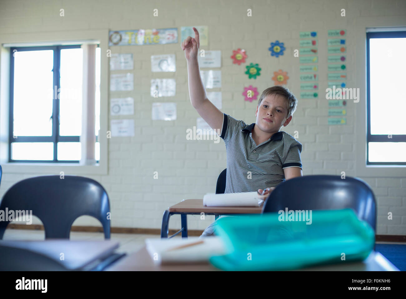 Schoolboy in classroom raising his hand Stock Photo - Alamy