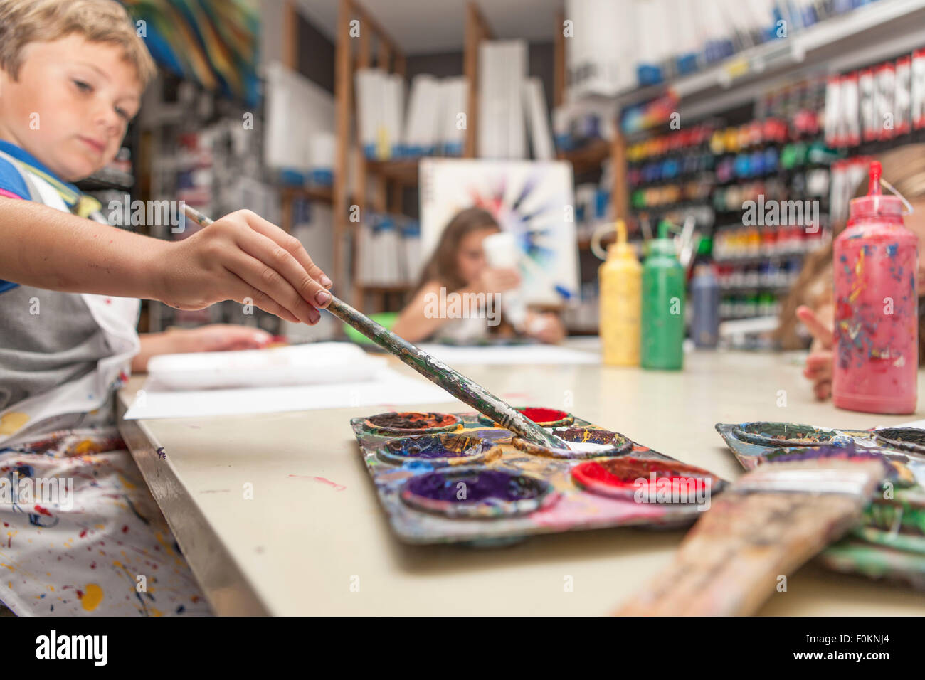 Boy using paint brush in an art class Stock Photo - Alamy