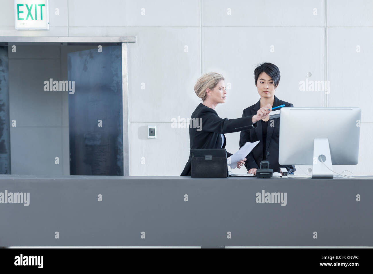 Two women behind reception desk in hotel lobby Stock Photo