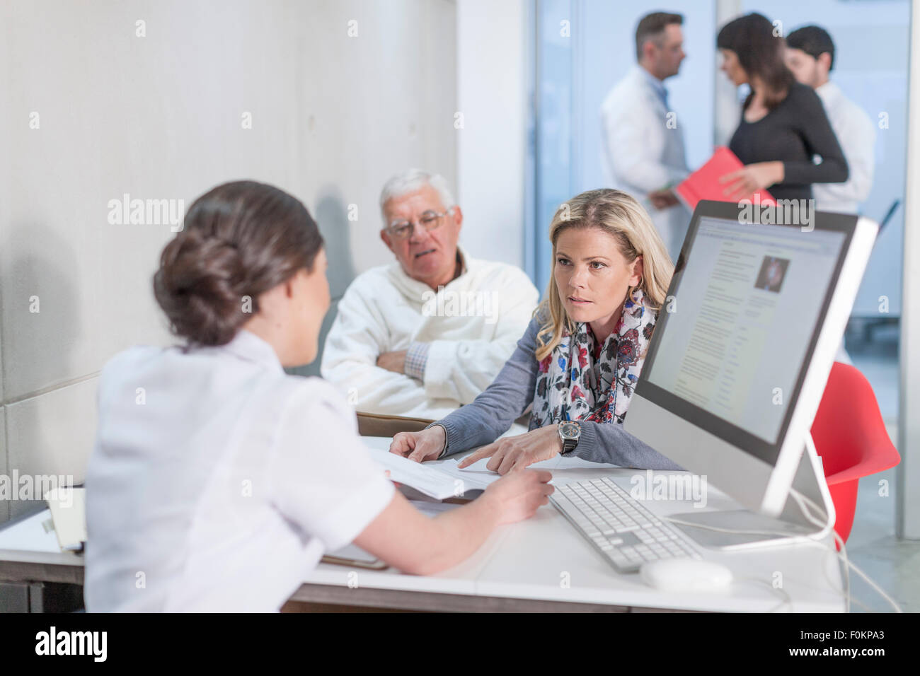 Nurse helping patients at clinic reception Stock Photo - Alamy
