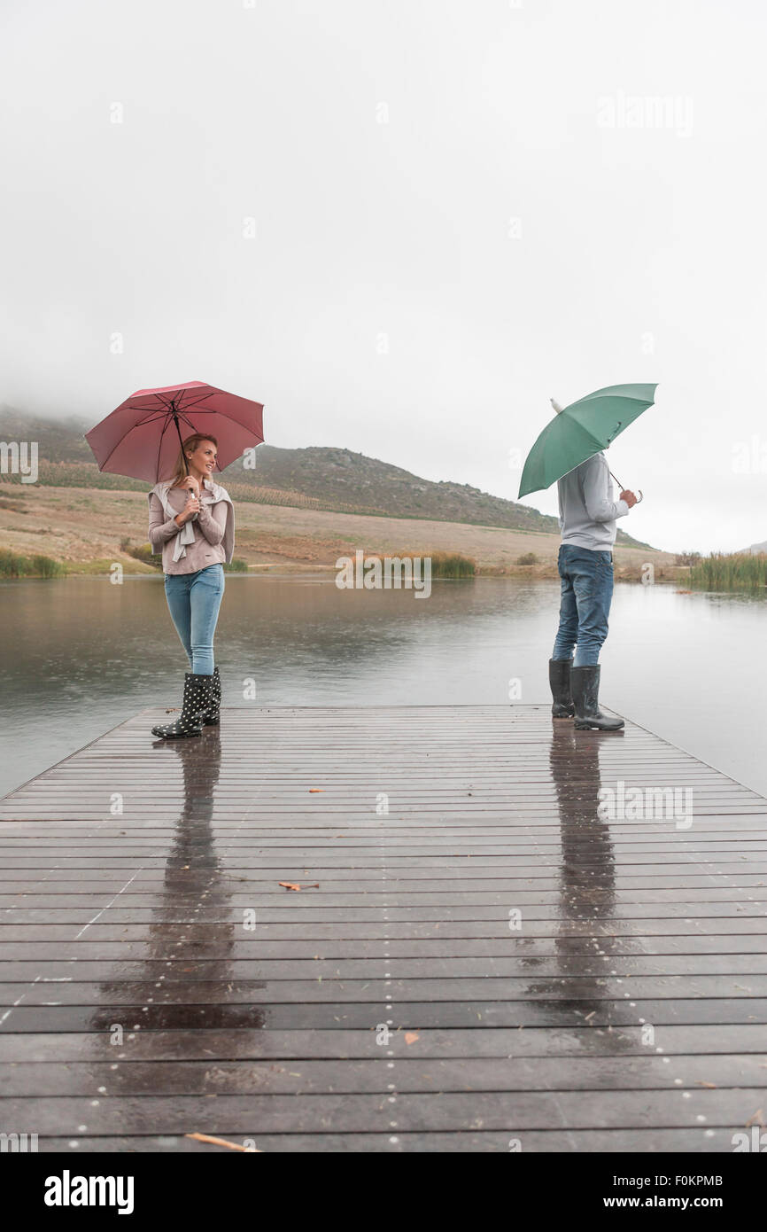 Couple standing in the rain on wooden boardwalk with umbrellas Stock ...
