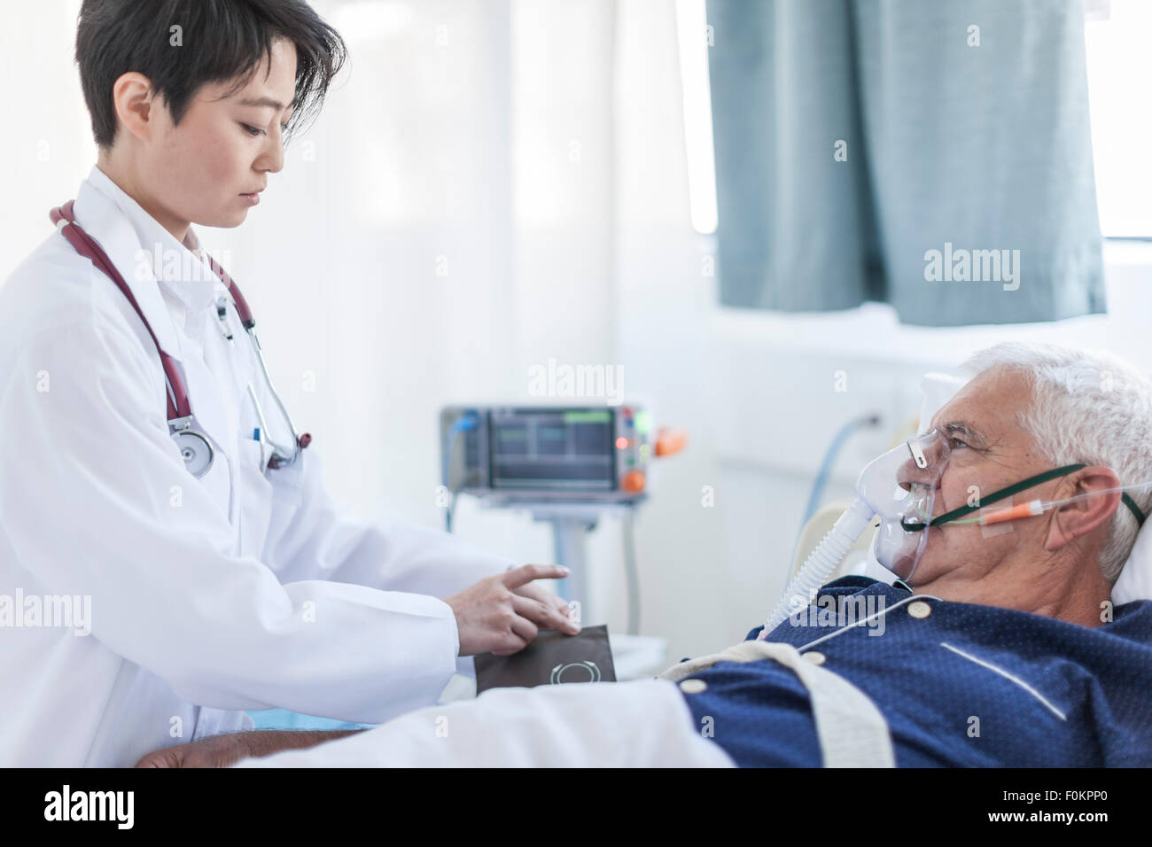 Doctor taking blood pressure of senior man with oxygen mask in a